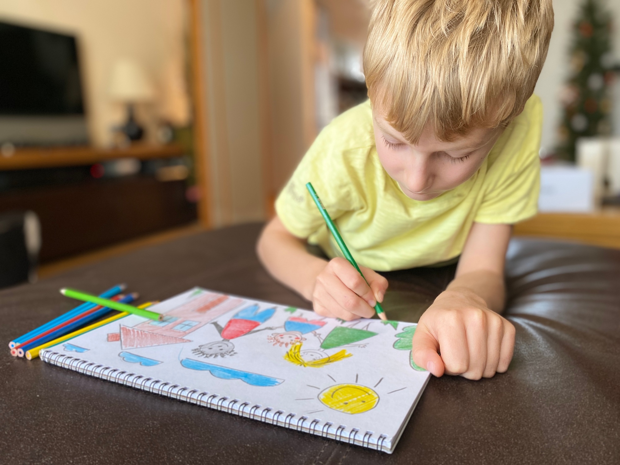 boy draws his family with colored pencils