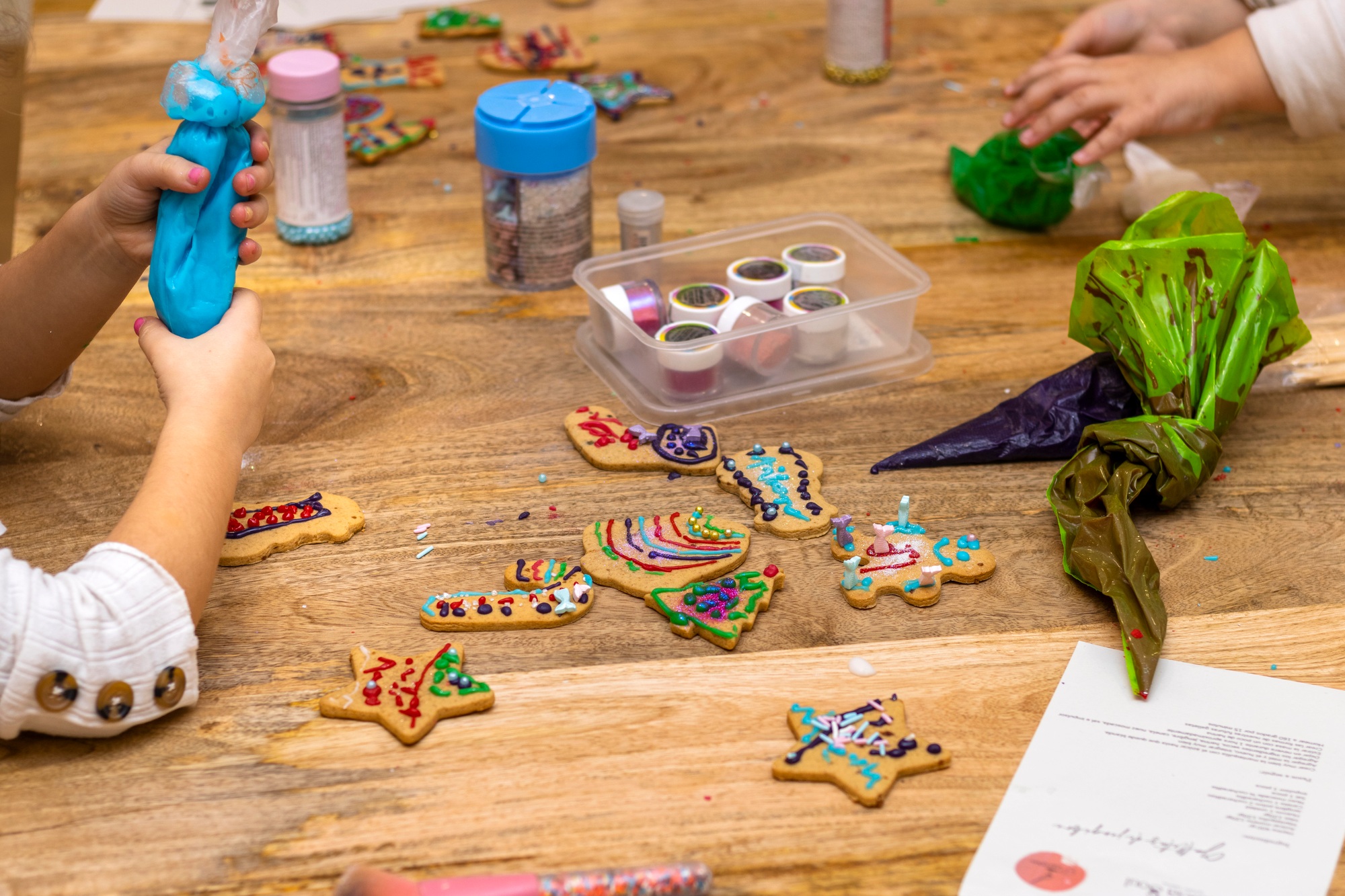 Christmas cookies workshop. Children decorating cookies with colorful pastry bags.