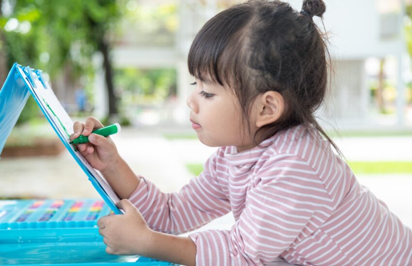 Little kids drawing with a colored pencil is a good activity for improving creative art